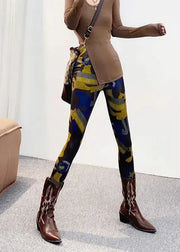 Person wearing colorful patterned leggings with brown boots on a neutral background