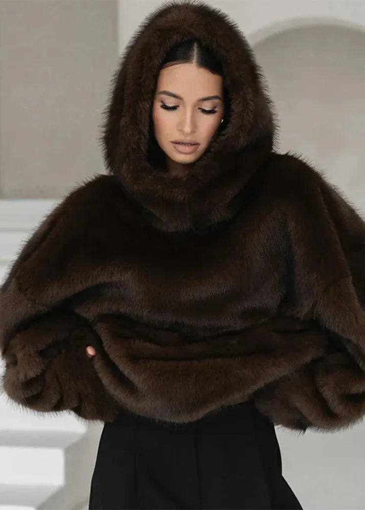 Woman wearing a brown fur hooded wrap against a neutral background