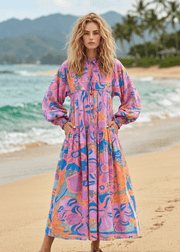 Woman in a colorful dress standing on a beach with 'arvin' branding.