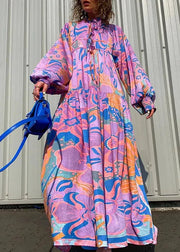 Person wearing a colorful patterned dress holding a blue handbag against a plain background