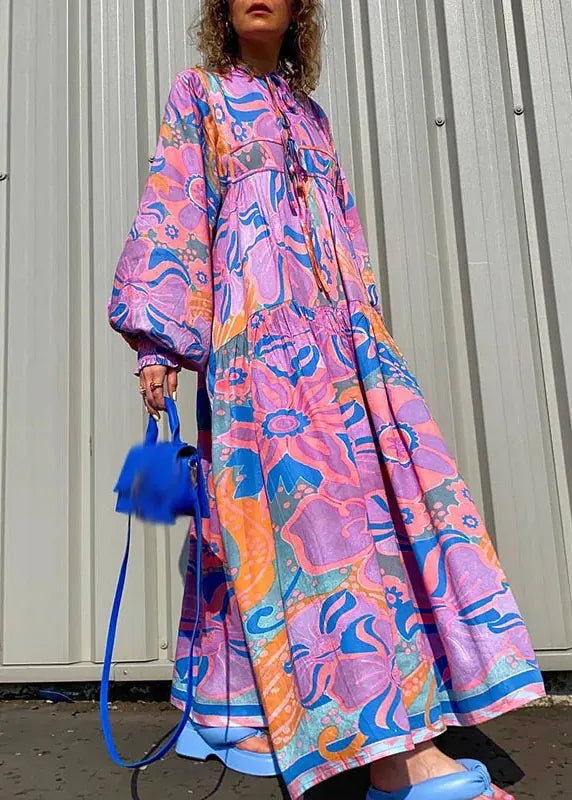 Person wearing a colorful floral dress holding a blue handbag against a plain background