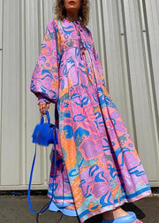 Person wearing a colorful floral dress holding a blue handbag against a plain background