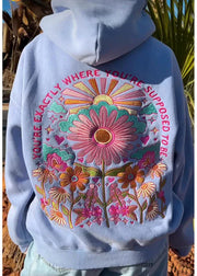 Light blue hoodie with colorful floral design and text on a natural background
