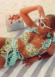 Woman in a floral bikini lying on a beach towel with a box of snacks in the background.
