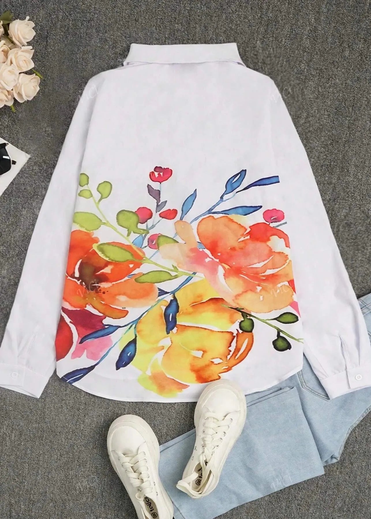 Floral-patterned shirt on a gray surface with white sneakers and a small plant.