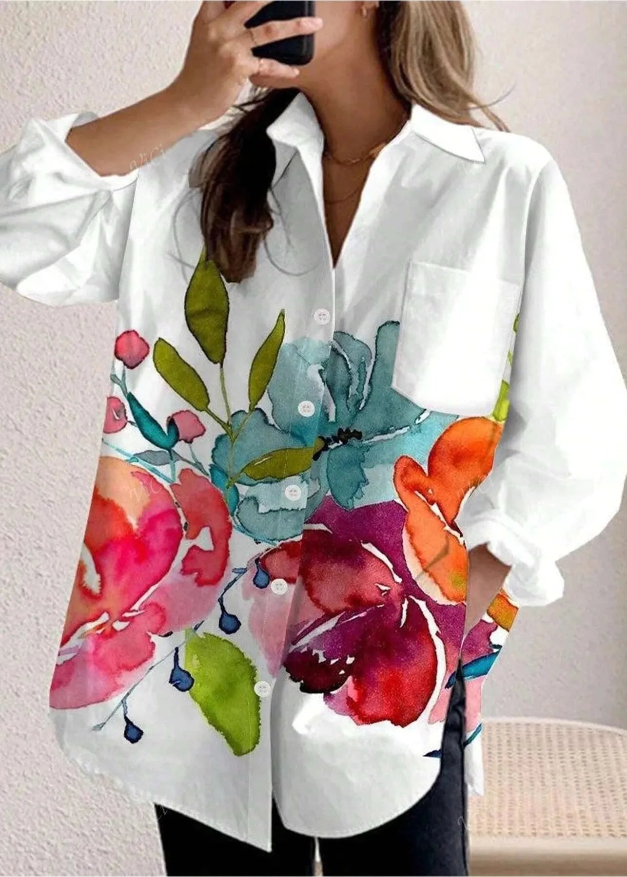 White shirt with colorful floral pattern worn by a person against a neutral background