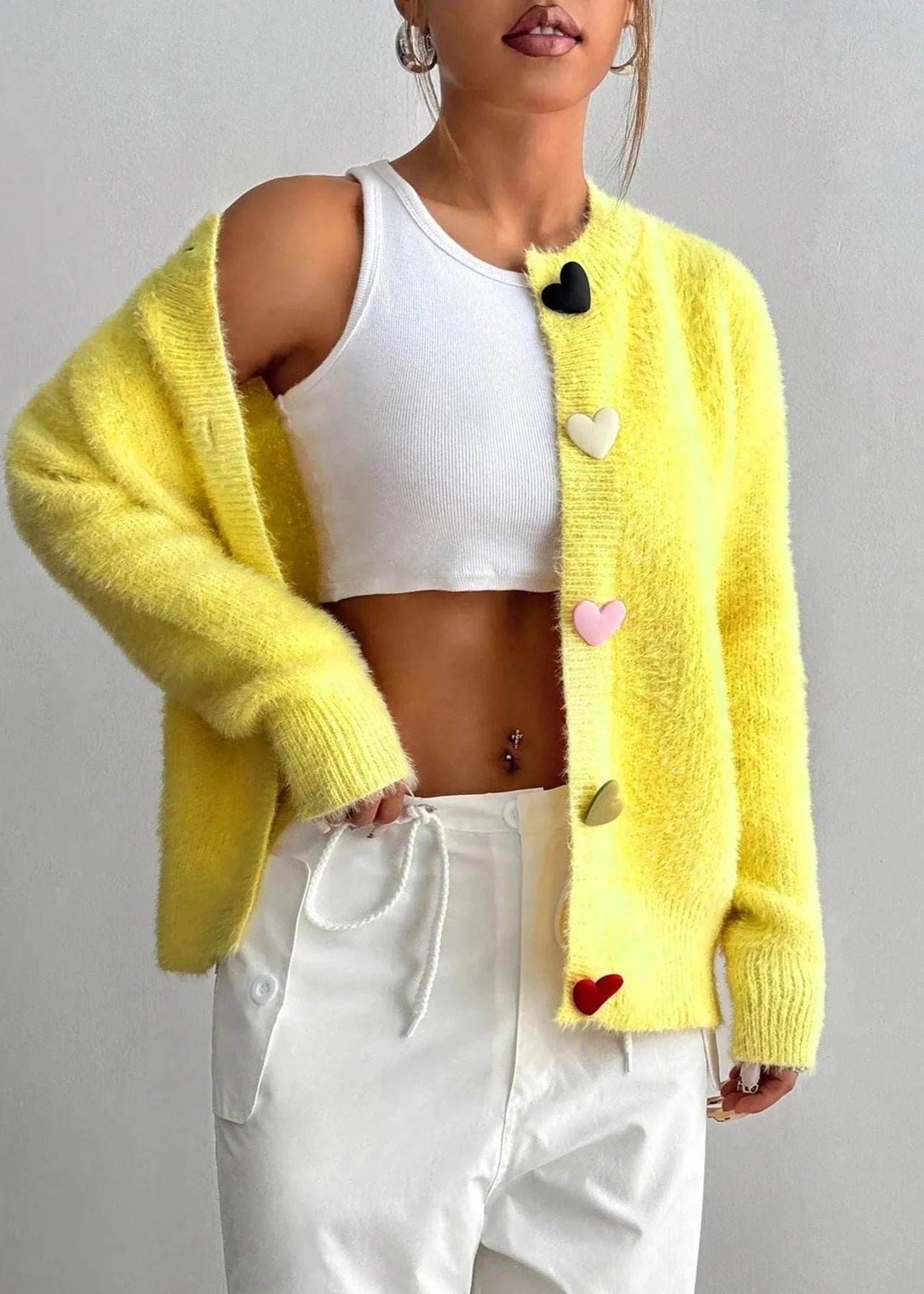 Person wearing a yellow cardigan with heart patterns on a gray background