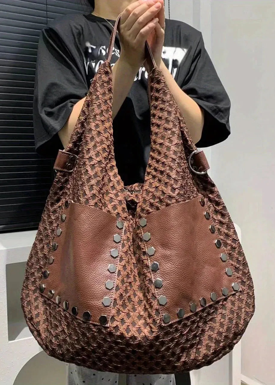 Person holding a brown textured handbag with studs against a neutral background
