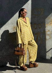 Woman in a yellow outfit standing against a textured wall.