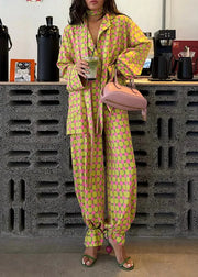 Person wearing a bright green and pink polka dot outfit holding a pink handbag in a coffee shop.