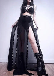 Person wearing a black outfit with high slit skirt and boots against a plain background