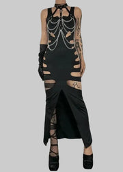 Person wearing a black, chain-embellished dress with cut-out designs against a white wall.