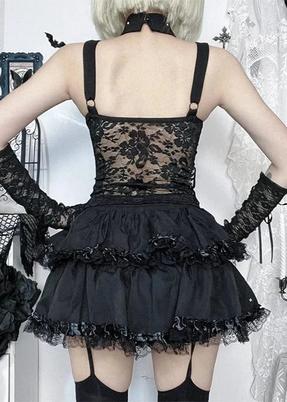 Person wearing a black lace dress with long gloves in a decorative setting.