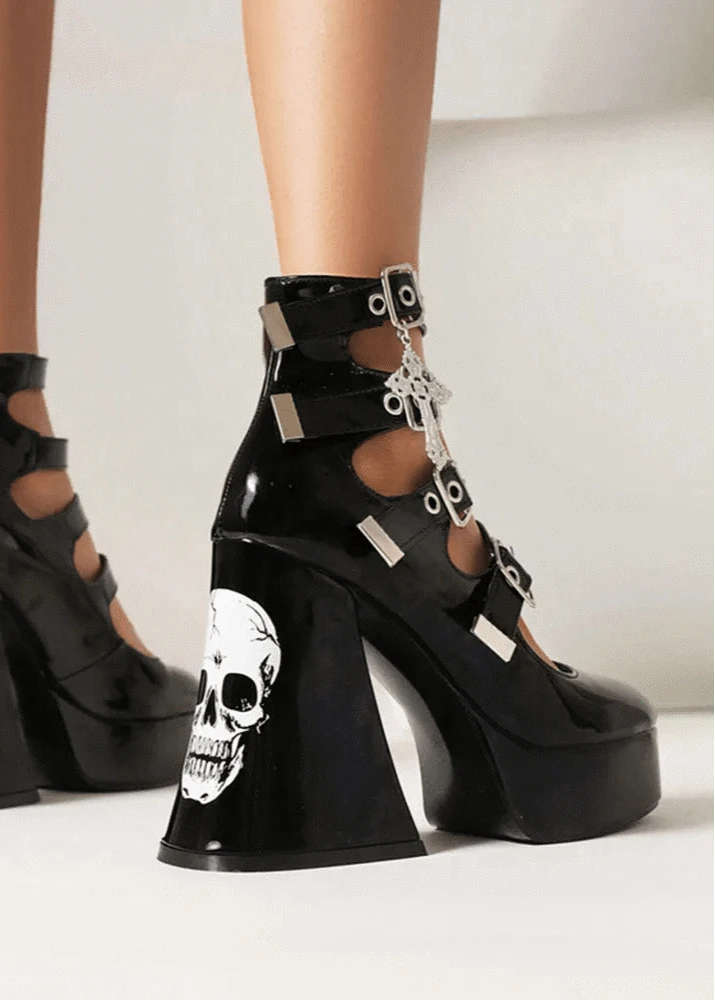 Black platform high-heeled shoes with skull designs on a neutral background