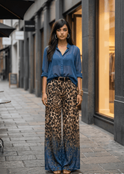 Woman in a blue shirt and leopard print pants standing on a city street with 'arvin' branding.