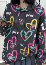 Person wearing a black hoodie with colorful heart designs and text.
