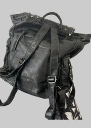 Black leather backpack on a patterned surface