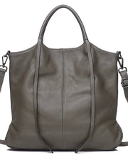 A large pebbled leather tote bag in a muted grayish green/olive tone, featuring dual top handles, a detachable shoulder strap, and a clean white background.