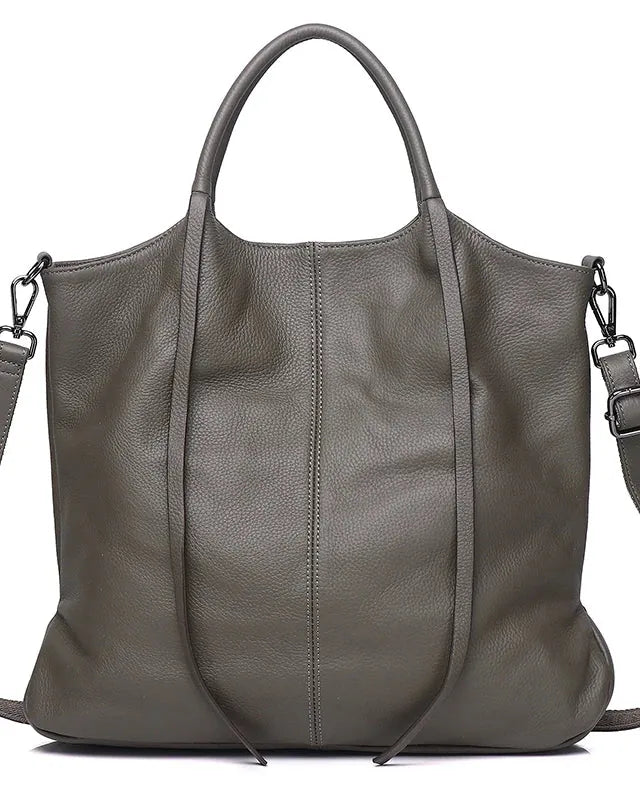 A large pebbled leather tote bag in a muted grayish green/olive tone, featuring dual top handles, a detachable shoulder strap, and a clean white background.