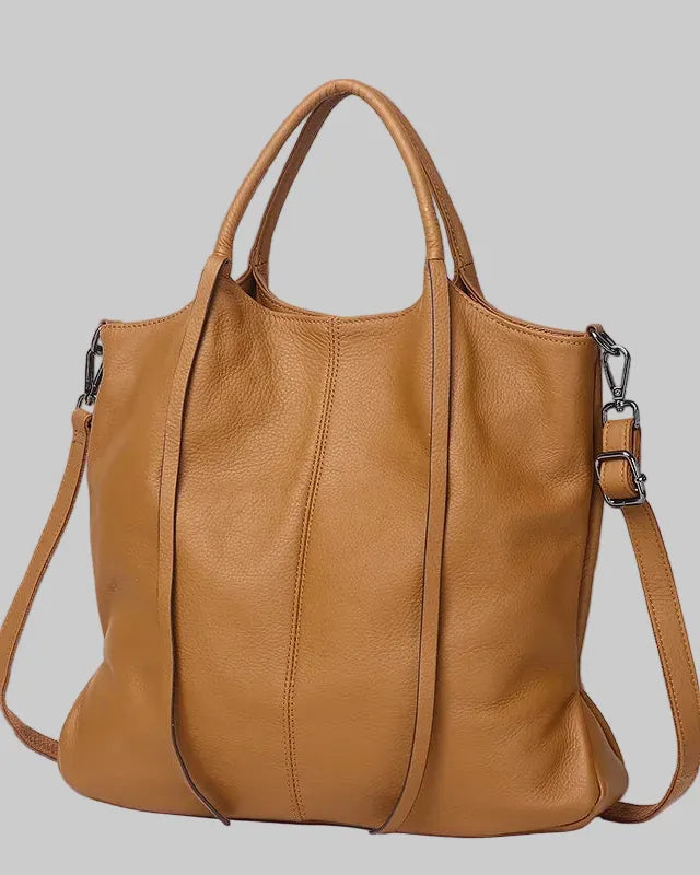 A tan cowhide leather shoulder bag with dual top handles and a detachable shoulder strap, shown against a light blue background with promotional text overlay.