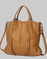 A tan cowhide leather shoulder bag with dual top handles and a detachable shoulder strap, shown against a light blue background with promotional text overlay.