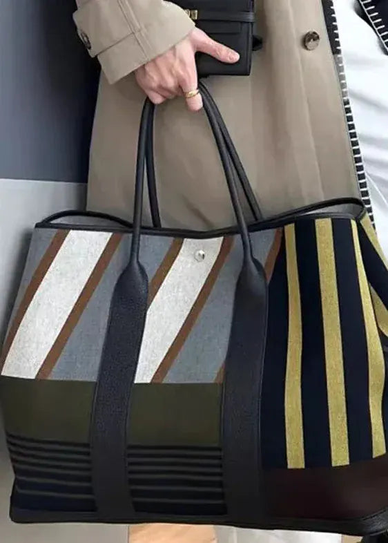 Person holding a striped tote bag with a neutral background