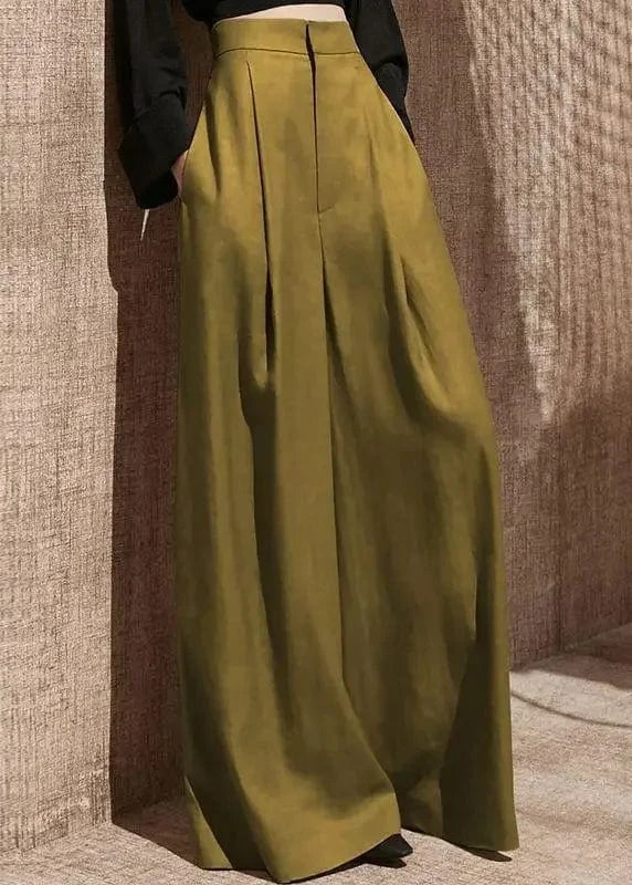 Green wide-leg pants worn by a person against a textured wall.