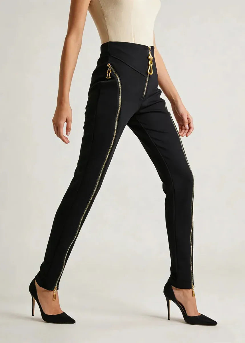 Black pants with gold zippers worn by a model on a white background