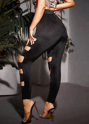 Person wearing black high-waisted pants with cut-out design, standing indoors.