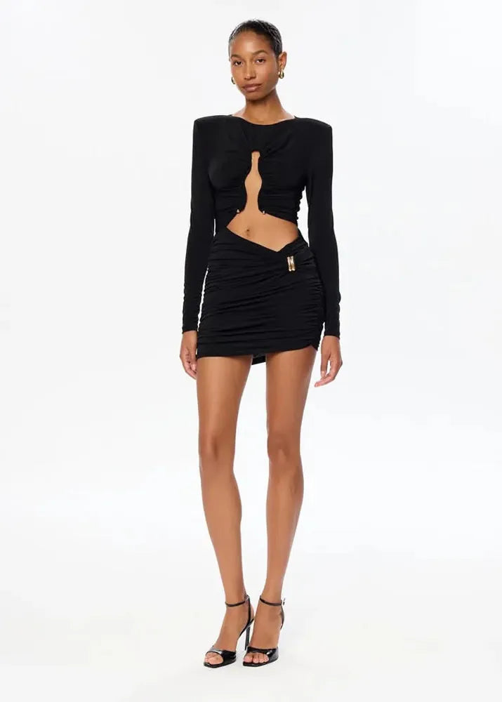 Woman wearing a black long-sleeve top and skirt set on a white background