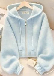 Light blue hoodie on a hanger with a pearl necklace and books in the background