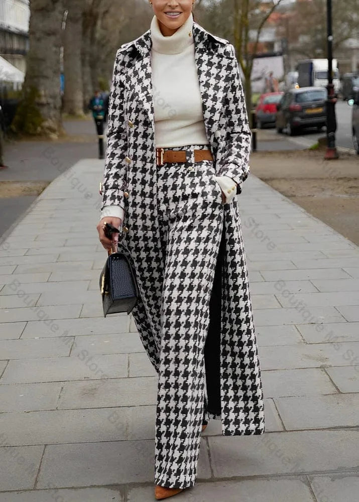 Person wearing a black and white houndstooth coat and pants on a city street.