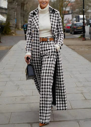 Person wearing a black and white houndstooth coat and pants on a city street.