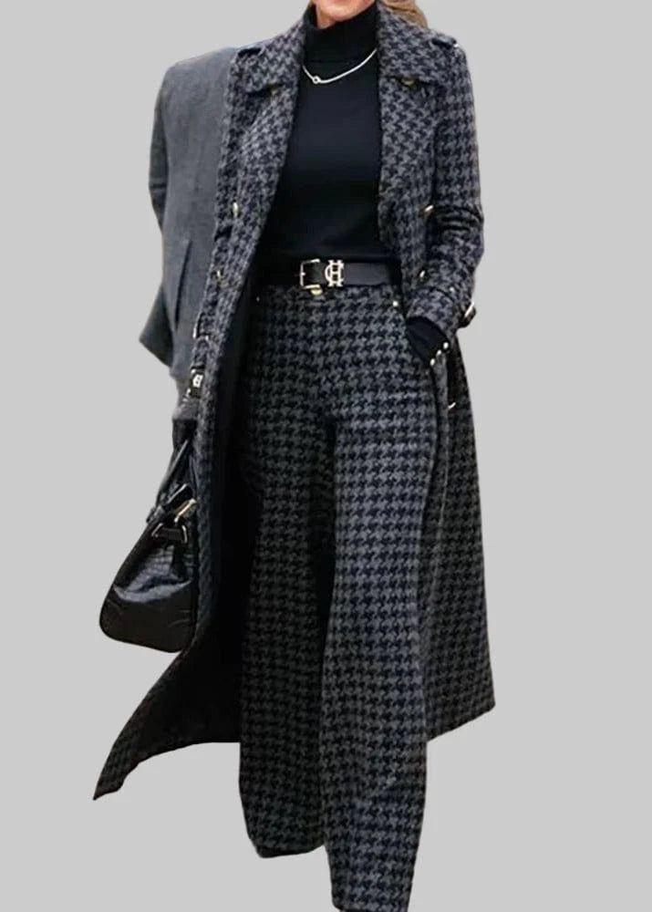 Person wearing a long coat and houndstooth patterned pants on a street.