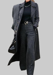 Person wearing a long coat and houndstooth patterned pants on a street.