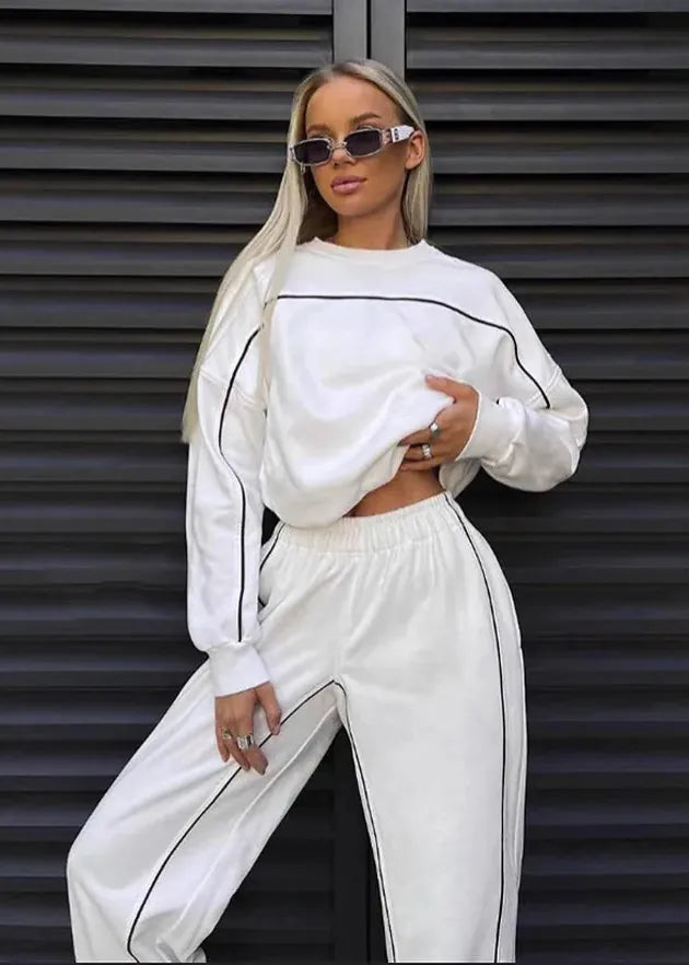Woman wearing a white outfit with black accents against a dark background