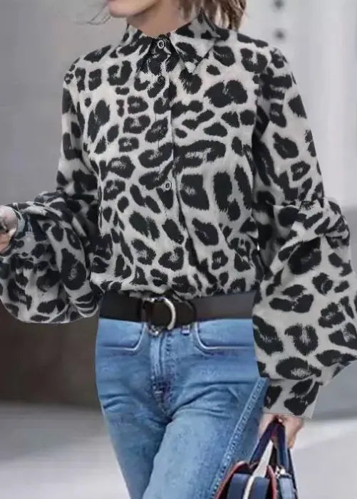 Person wearing a leopard print blouse with long sleeves and blue jeans.