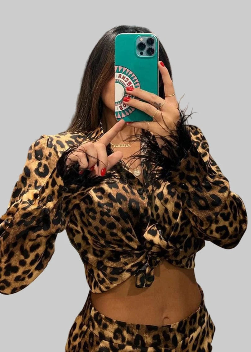 Person wearing a leopard print outfit taking a mirror selfie.