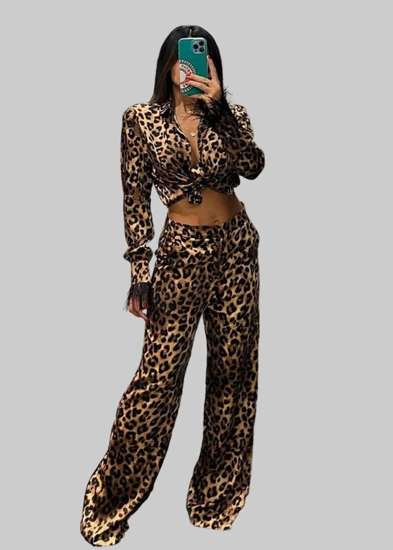 Person wearing a leopard print outfit taking a mirror selfie in an indoor setting.