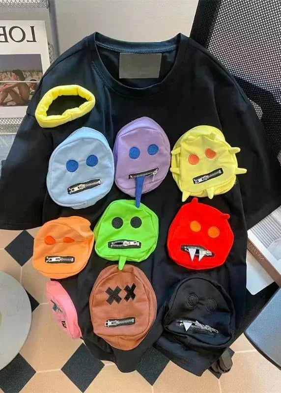 Black sweatshirt with colorful emoji-style patches on a patterned surface.
