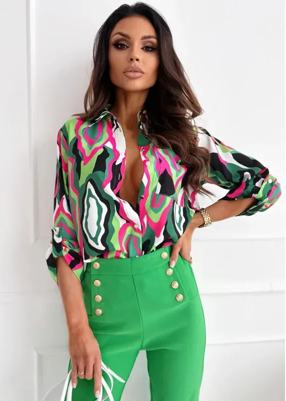 Woman wearing a colorful patterned blouse and green pants against a white background