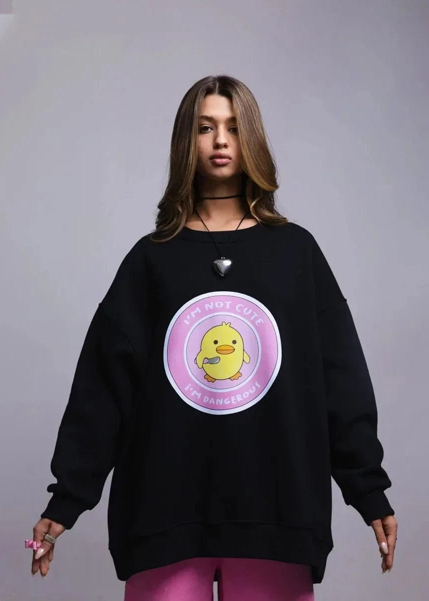 A woman wearing a loose fit grey sweatshirt with a round neck and a graphic print on the front.