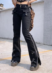 Black high-waisted flare pants with multiple silver metal rings, utility pockets, and side zippers, shown on a model standing outdoors on a concrete surface.