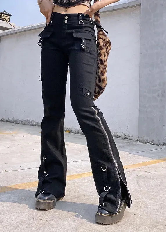 Black high-waisted flare pants with multiple silver metal rings, utility pockets, and side zippers, shown on a model standing outdoors on a concrete surface.
