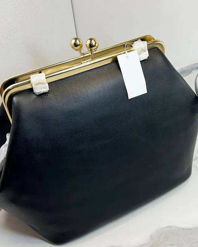 Black handbag with gold clasp on a white surface