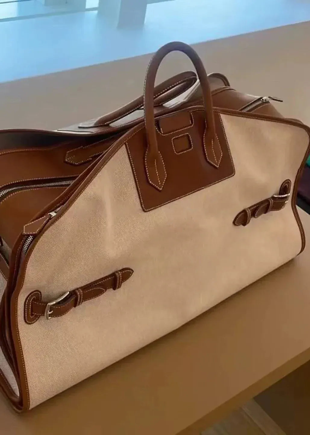 Large beige and brown handbag on a light surface