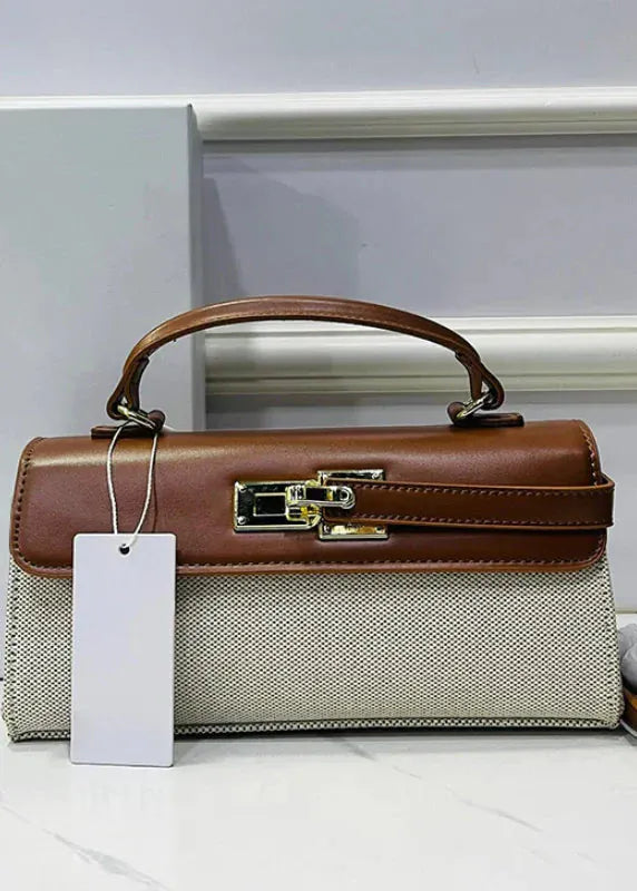 Brown and beige handbag with a tag on a white surface
