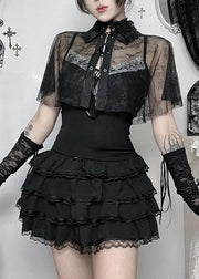 Person wearing a black lace outfit with sheer sleeves in a decorative room.
