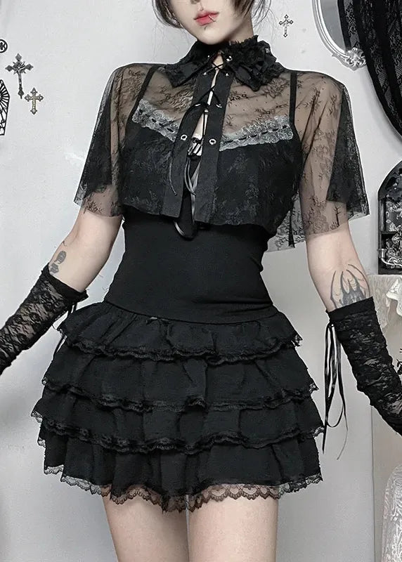Person wearing a black lace outfit with sheer sleeves in a decorative room.