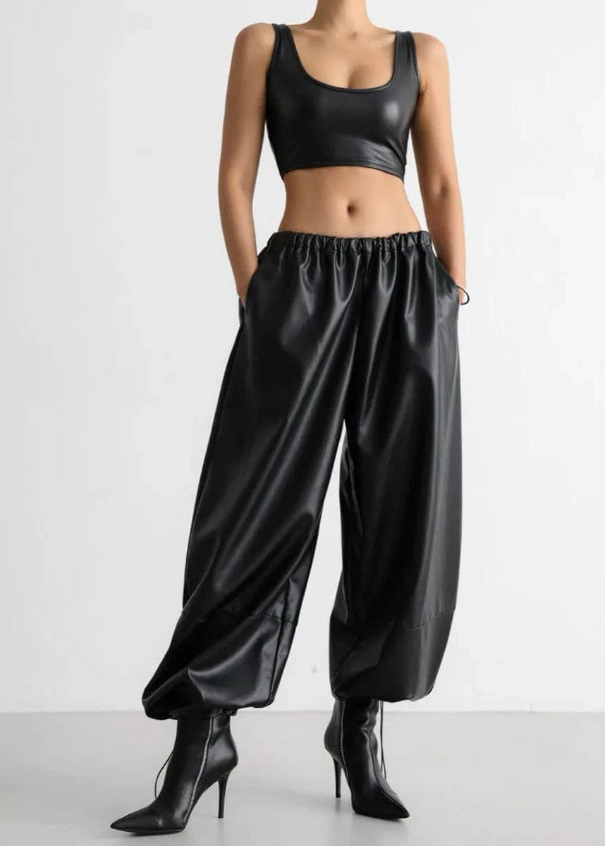 Person wearing a black satin outfit with a crop top and wide-leg pants on a white background